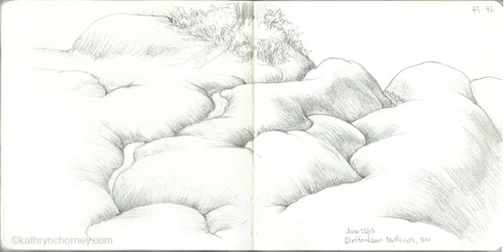 A sketch without colour focuses on the folding, intersecting forms of the badland hills.